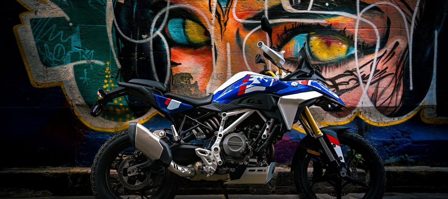 Blue and white adventure bike against a graffiti wall of giant painted eyes