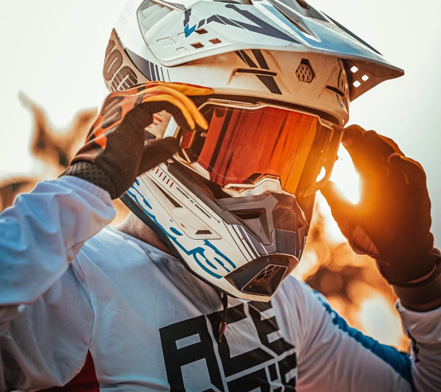 Rider adjusting goggles, sun flaring through the visor